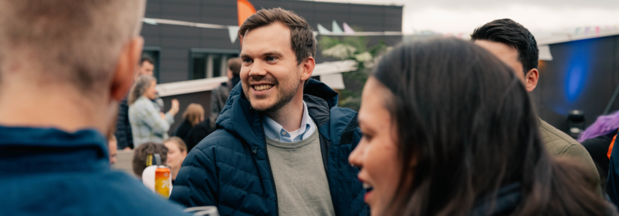 Ung smilende mann omringet av flere mennesker