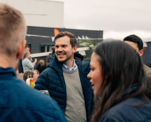 Ung smilende mann omringet av flere mennesker